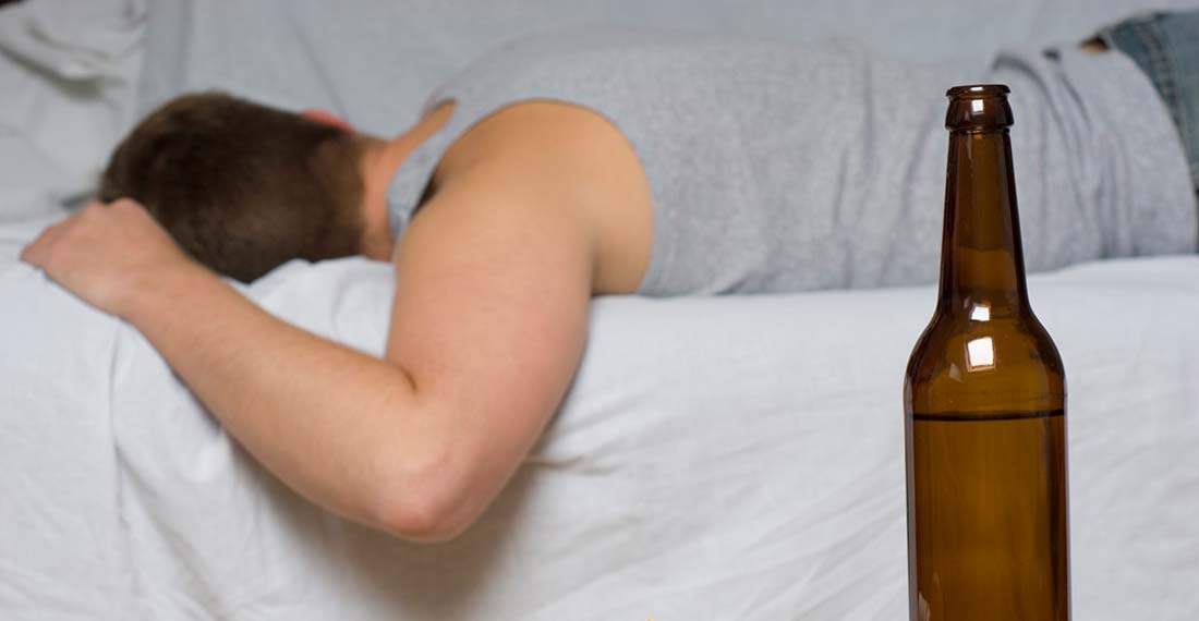 мужчина лежит на кровати рядом с бутылкой пива